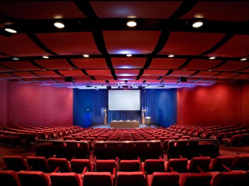an empty auditorium with red chairs and a screen at Sofitel Melbourne On Collins in Melbourne