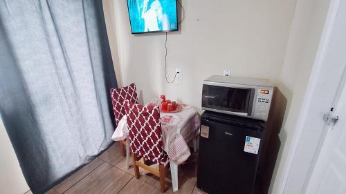 uma pequena cozinha com uma mesa e um micro-ondas em KITNET k1 em TORRES-RS - Na mais bela praia Gaúcha - 2 quartos - Frigobar - micro-ondas - banheiro - ar condicionado split - TV smart 32' - Wi-Fi - Anfitriã Superhost no BnB em Torres