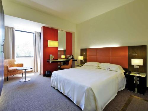 a hotel room with a large bed and a chair at Mercure Reggio Emilia Centro Astoria in Reggio Emilia