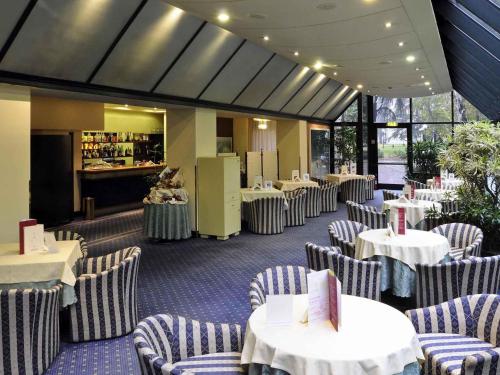 a dining room with white tables and chairs and a restaurant at Mercure Reggio Emilia Centro Astoria in Reggio Emilia