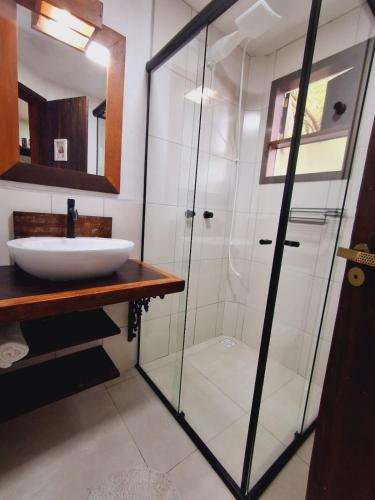 a bathroom with a glass shower and a sink at Vila Artesania in Bombinhas