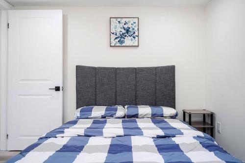 ein Schlafzimmer mit einem Bett mit einer blau-weißen Bettdecke in der Unterkunft Bright & Cozy Home in the GTA (Basement Apartment) in Whitby