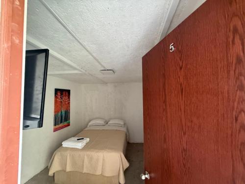 a small room with a bed and a door at La Vecindad in Querétaro
