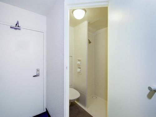 a white bathroom with a toilet and a light at ibis Budget - Enfield in Sydney