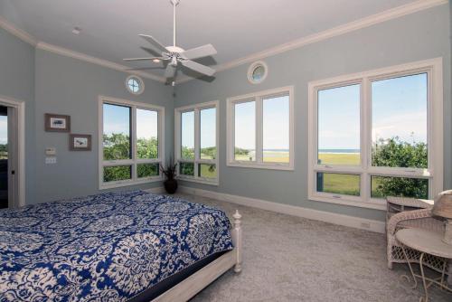 a bedroom with a bed and windows and a ceiling fan at Moonrise Point in Edisto Island