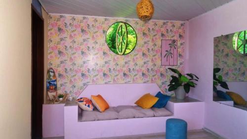a pink room with a couch with colorful pillows at Pousada Sol de Berlinque in Vera Cruz de Itaparica