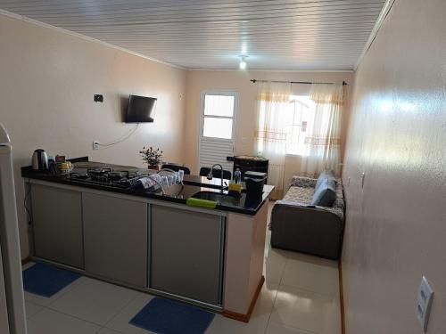 a kitchen with a stove and a couch in a room at Apart hotel - 2 tranquilidade e conforto de casa in Tuparendi