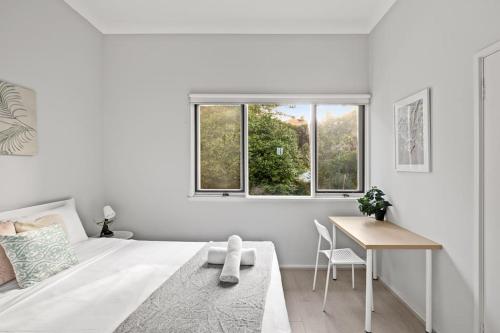 a white bedroom with a bed and a table at Modern Private Double Room - Centrally Located - Shared Bathroom