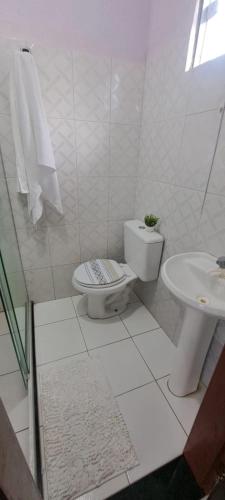 a white bathroom with a toilet and a sink at Pousada Sol de Berlinque in Vera Cruz de Itaparica