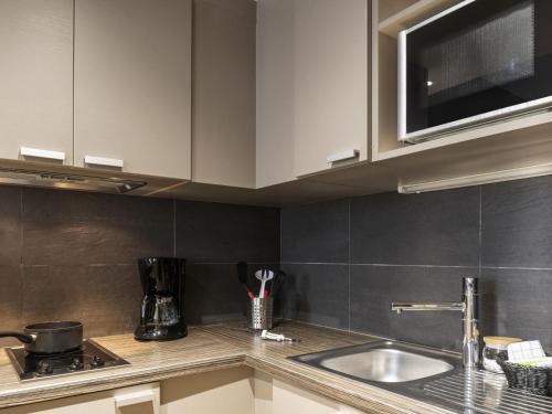 a kitchen with a sink and a microwave at Aparthotel Adagio La Défense Esplanade in Puteaux