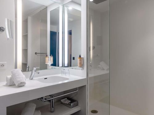 a white bathroom with a sink and a shower at Mercure Annecy Centre in Annecy