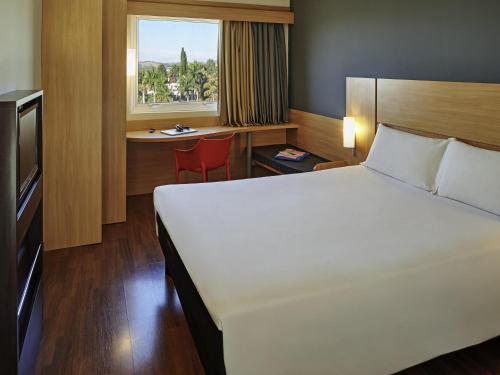 a bedroom with a bed and a desk and a window at ibis Sorocaba in Sorocaba