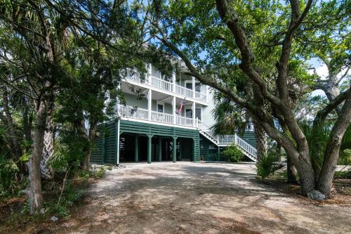 a large white building with a balcony and trees at Tequila Sunset in Edisto Island
