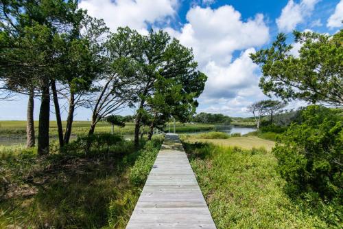 a wooden pathway through a field with trees and a lake at Tequila Sunset in Edisto Island