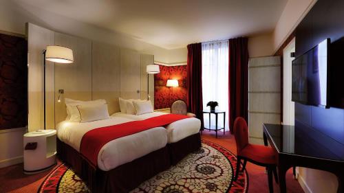 a hotel room with a bed and a flat screen tv at Carlton Hotel Lyon - MGallery Collection in Lyon