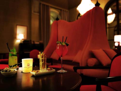 a table with a glass of wine and a plate of food at Carlton Hotel Lyon - MGallery Collection in Lyon