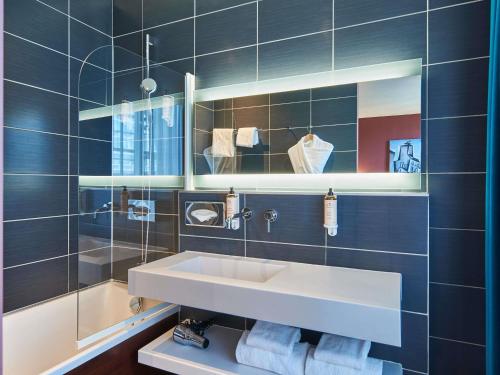 a blue tiled bathroom with a sink and a mirror at Mercure Paris Tour Eiffel Pont Mirabeau in Paris