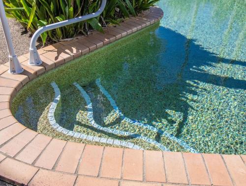 a pool of water next to a brick walkway at Sunrise Cove 25 in Kingscliff