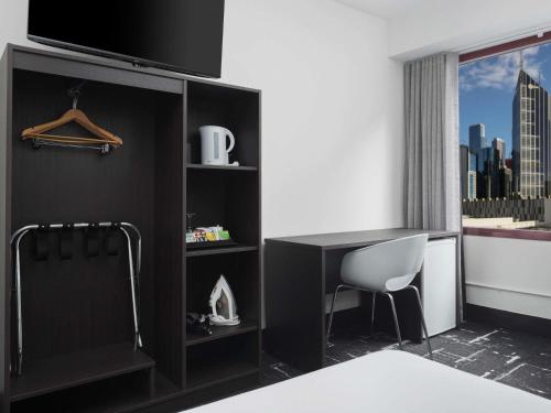 a hotel room with a desk and a tv at Mercure Welcome Melbourne in Melbourne