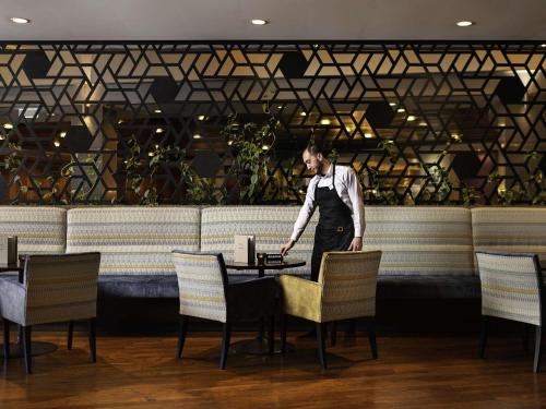 a man standing at a table in a restaurant at ibis Auckland Ellerslie in Auckland