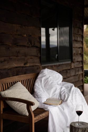 a bed with a book and a glass of wine at Chalet Tasmania in Judbury