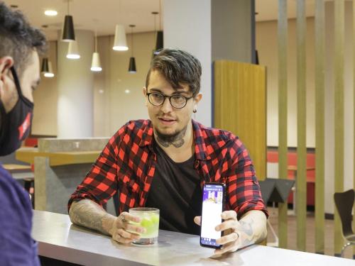 a man sitting at a table holding a cell phone at ibis Sao Jose dos Campos Dutra in São José dos Campos