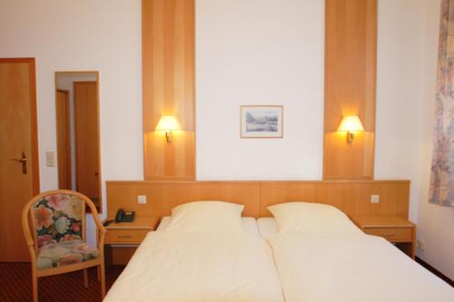 a bedroom with a bed and a chair and two lights at Hotel Pension Kaden in Dresden
