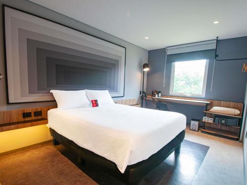 a large white bed in a room with a window at Ibis Monterrey Aeropuerto in Monterrey