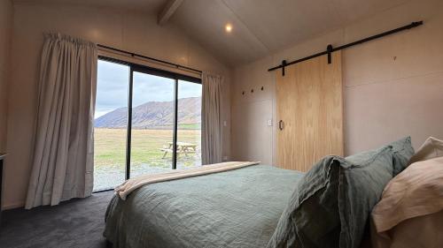 Un dormitorio con una cama y una ventana grande. en Sleep under the stars at Manuka Starlight, en Twizel