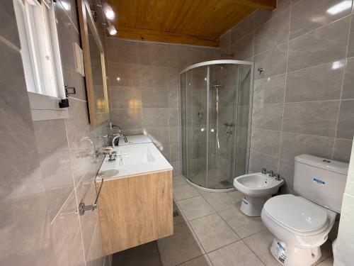 Un baño con inodoro, lavabo y ducha. en La Casita Cosquín, en Cosquín