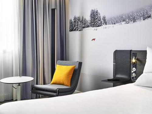 a room with a bed and a chair and a table at Novotel Edinburgh Centre in Edinburgh