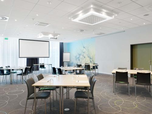 a conference room with tables and chairs and a screen at Novotel Berlin Mitte in Berlin