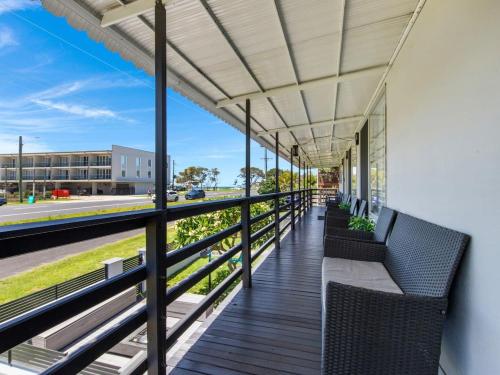 a balcony with chairs and awnings on a building at Skyes Beach House-Views, Spas, Sauna, Arcade Games in Surf Beach