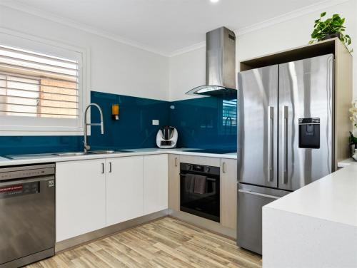 a blue and white kitchen with a refrigerator at Skyes Beach House-Views, Spas, Sauna, Arcade Games in Surf Beach