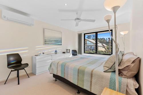 Un dormitorio con una cama y un escritorio y una ventana. en Sandy Place Beach House managed by Batemans Bay Accom, en Long Beach