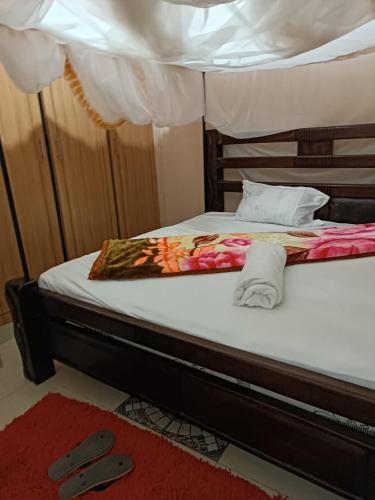 a bed with two slippers on the floor next to it at Mango Plaza in Homa Bay