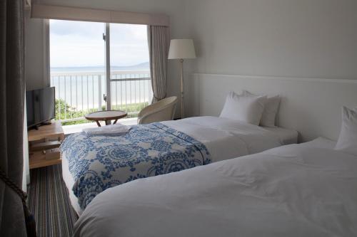 a hotel room with two beds and a balcony at WITH SEA Nakama in Onna