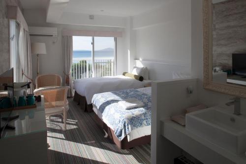 a bedroom with a bed and a bathroom with a sink at WITH SEA Nakama in Onna