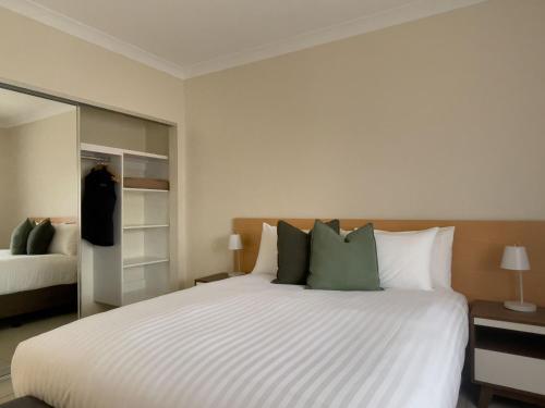 Un dormitorio con una gran cama blanca con almohadas verdes. en The Phoenix Artesian Spa Resort and Accommodation, en Moree