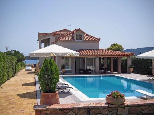 a villa with a swimming pool in front of a house at Ermioni Villas in Ermioni