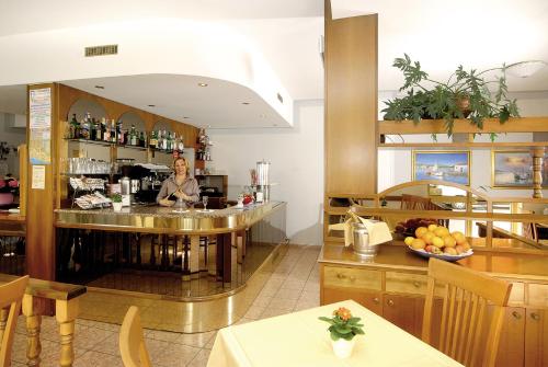 a woman standing behind a bar in a restaurant at Albergo Savoia in Ospedaletti