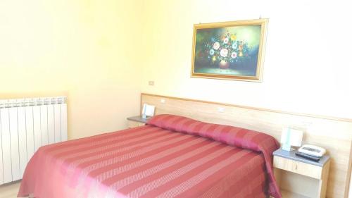 a hotel room with a bed with a striped blanket at Albergo Savoia in Ospedaletti