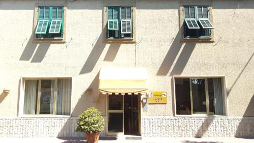 a building with blue windows and a plant in front of it at Albergo Savoia in Ospedaletti