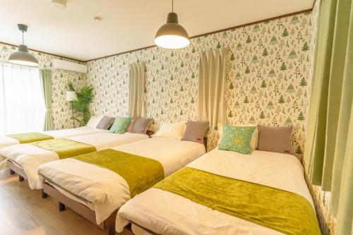 a group of four beds in a room with wallpaper at ジブリパークまで車10分 遊べるキッズハウス1棟貸切り 敷地内無料駐車場あり 最大12名 in Seto