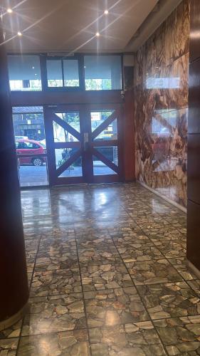 a lobby with a large glass door and a stone floor at Studio Arena y Sol - MDQ Güemes in Mar del Plata