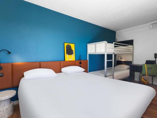 Un dormitorio con una cama blanca y una pared azul. en ibis Auch, en Auch