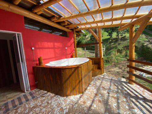 a wooden bath tub in a room with a red wall at Sitio Mangala in Itapeva