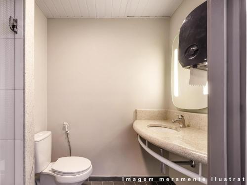 a bathroom with a toilet and a sink at ibis Guarulhos Aeroporto in Guarulhos