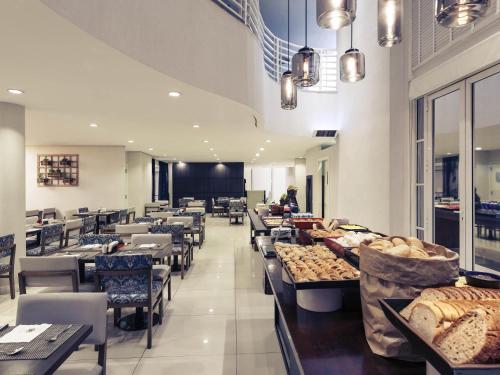a dining room with tables and chairs and a cafeteria at Mercure Campinas in Campinas