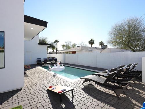 a swimming pool with chairs and a person in a swimming pool at LUXE - Nouveau - Sparkling Pool - Walk to Old Town in Scottsdale